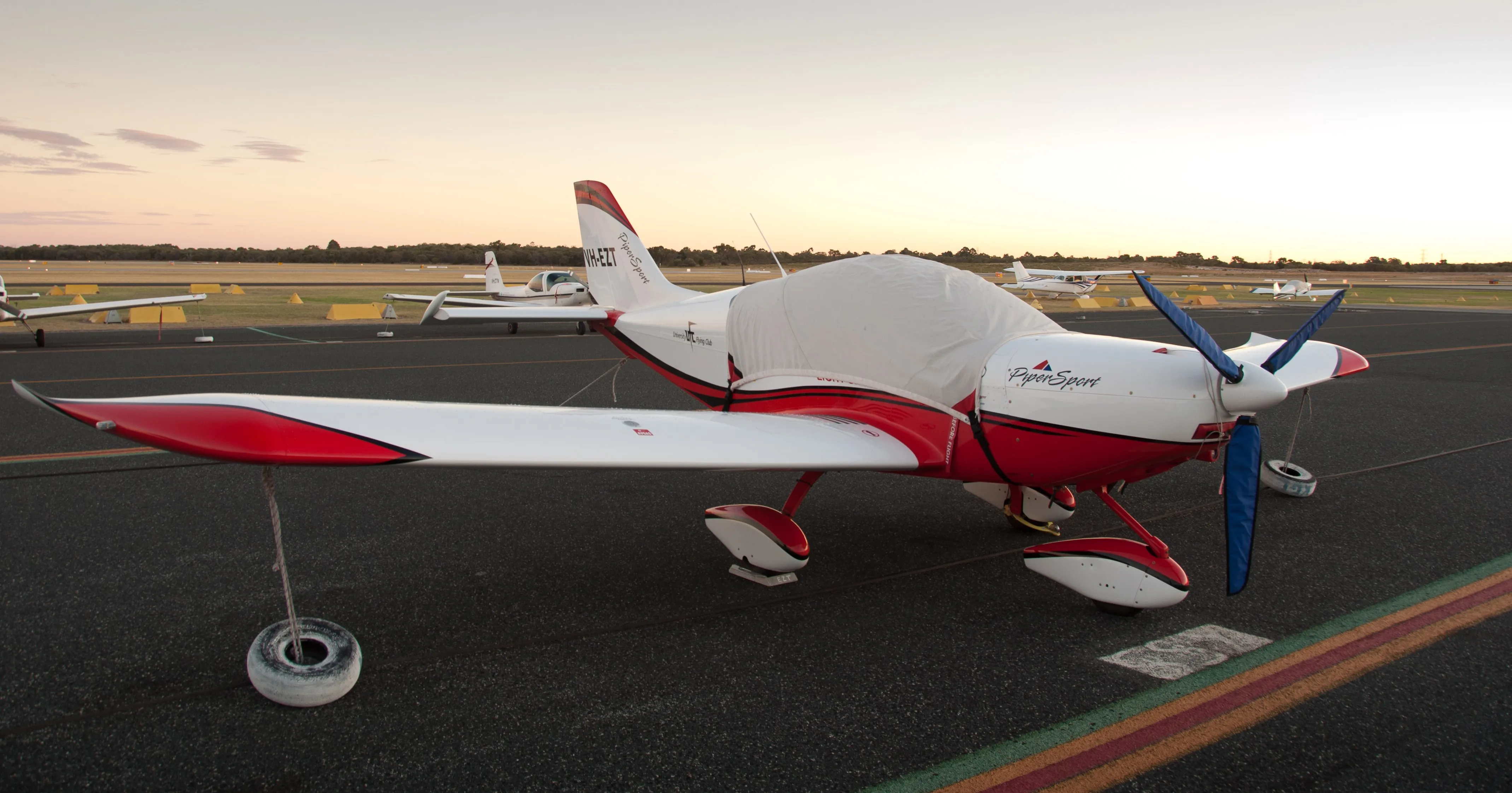 VH-EZT tied down under its cover on the Jandakot apron at dusk