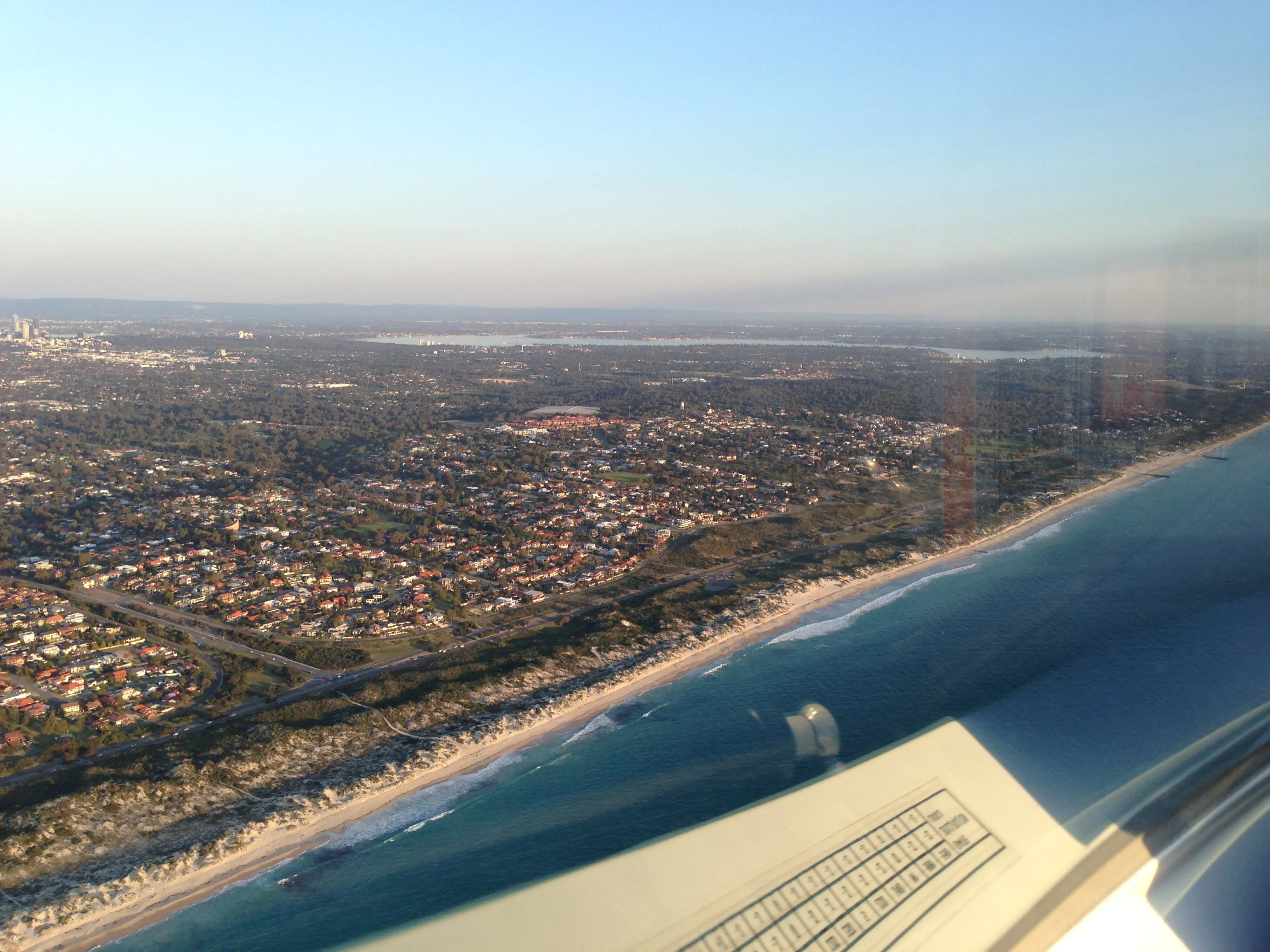 Perth's coastline and distant city skyline seen over VH-EZT's wing