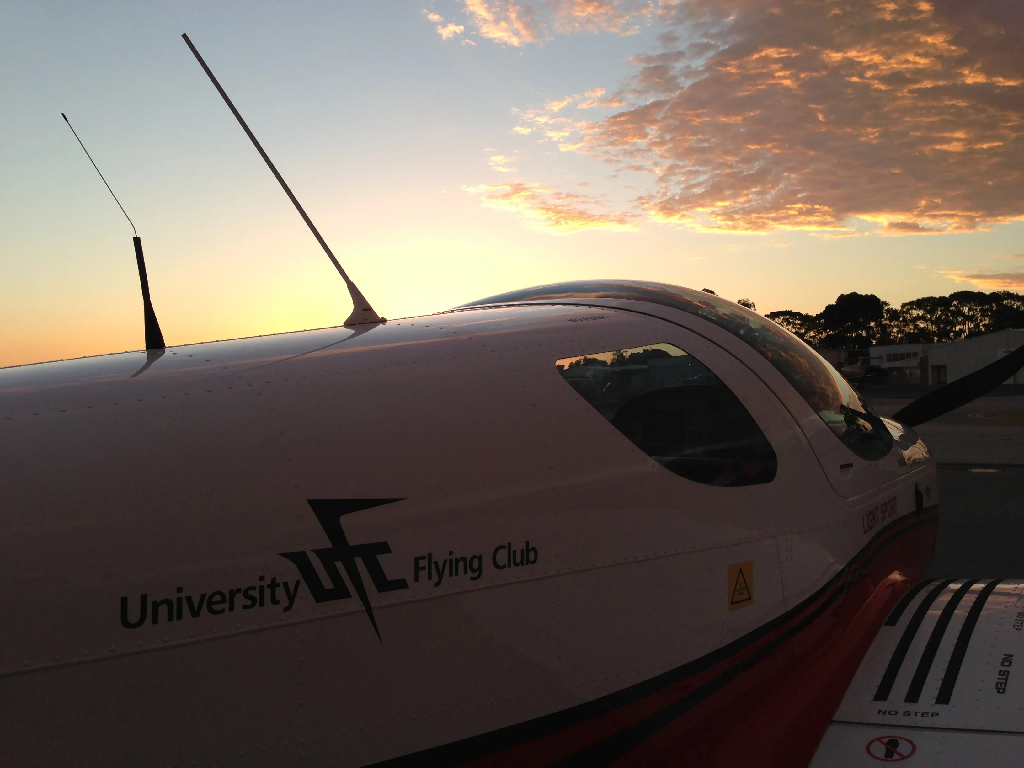 University Flying Club titles on VH-EZT's fuselage at sunset