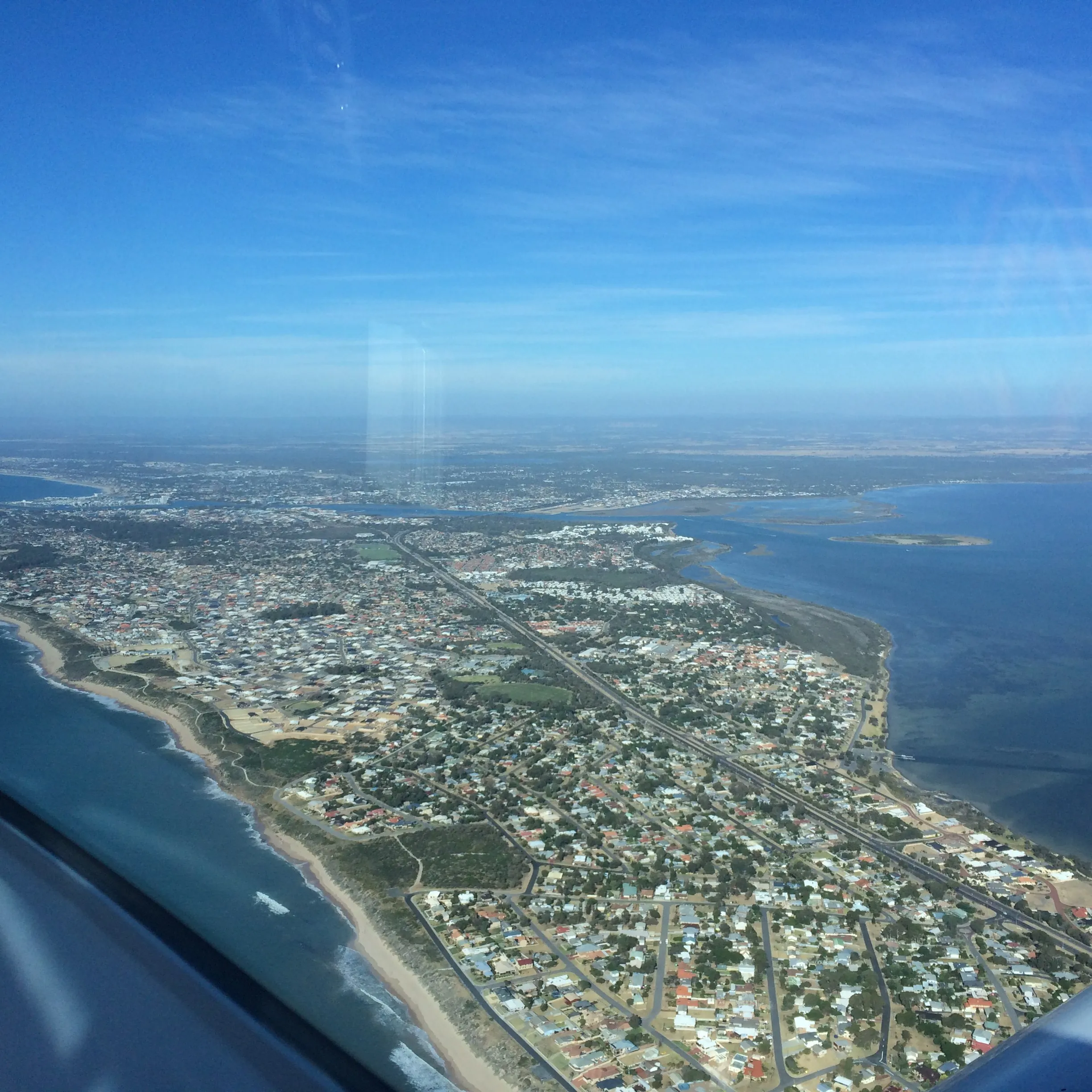 The strip of suburbs between the ocean and the Peel Estuary near Mandurah, seen from VH-EZT