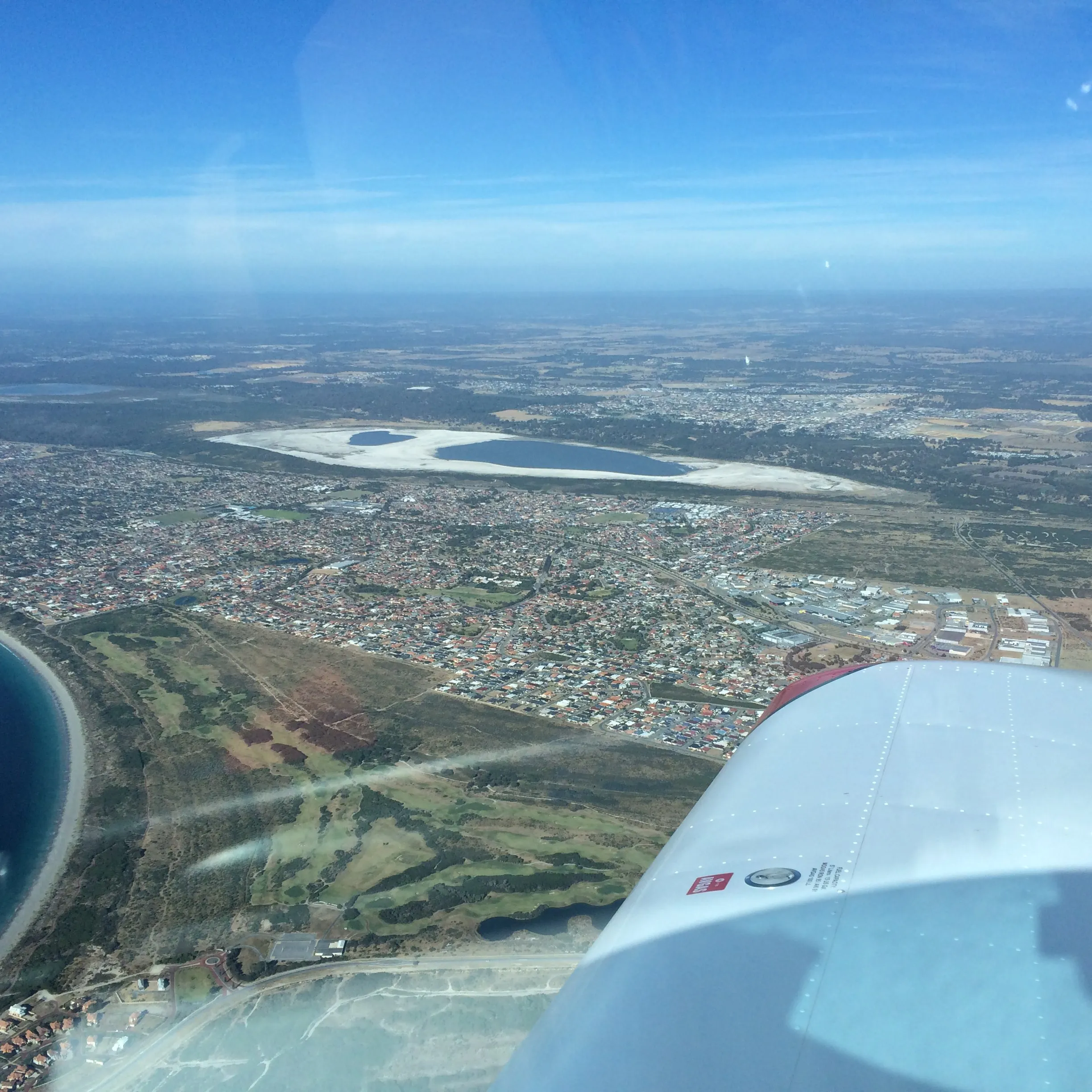 Coastal suburbs and a salt-rimmed lake south of Perth seen from VH-EZT